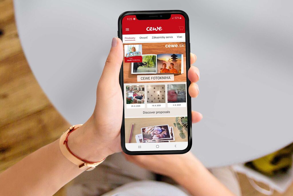 Osoba drží smartfón s aplikáciou CEWE v ruke.