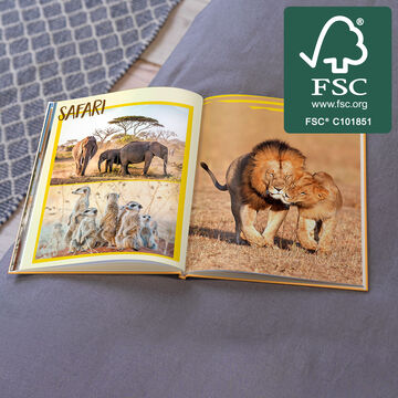 Otvorená fotokniha so safari fotkami: levy a slony v prírode.